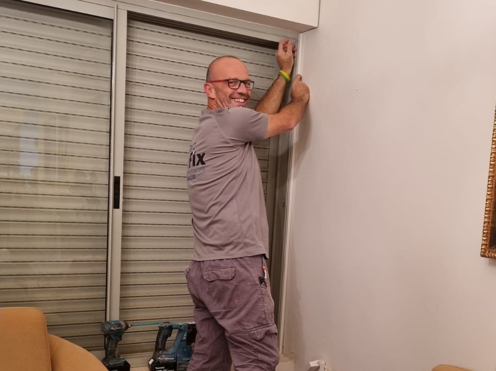 משה וויסמן בחולצת NET-FIX מתקין נקודת רשת בסלון של לקוח